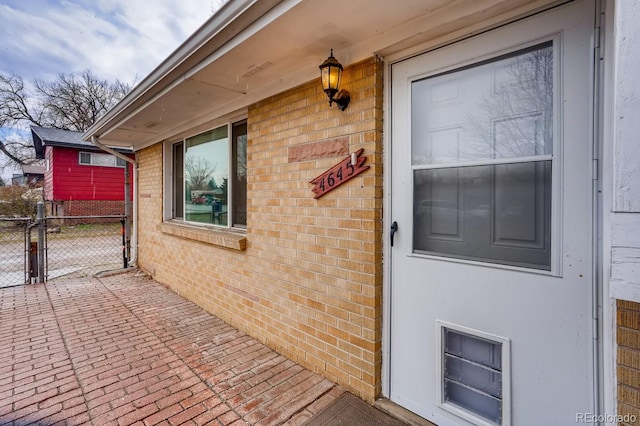 property entrance featuring brick siding, fence, and a gate