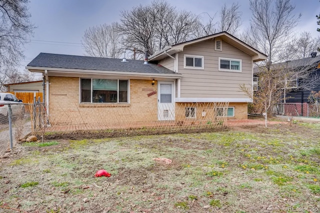 split level home with brick siding, fence, and a shingled roof