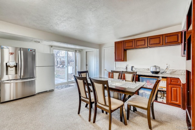 dining space with a textured ceiling and light colored carpet