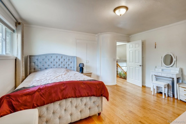 bedroom with wood finished floors, crown molding, and multiple windows