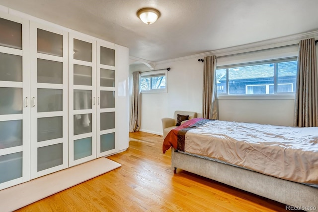 bedroom with light wood-style flooring and crown molding