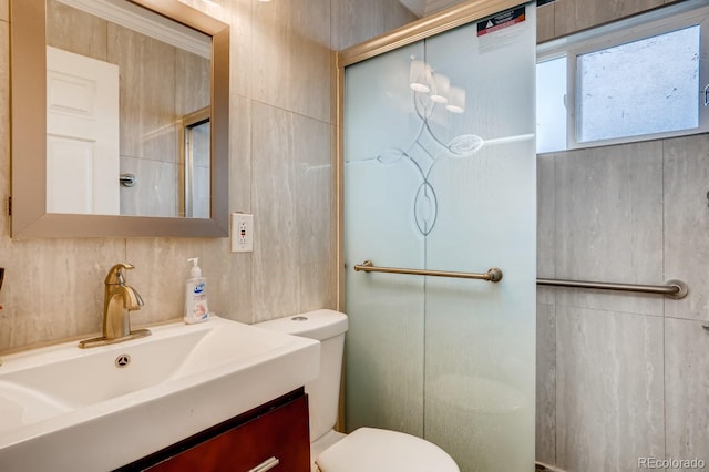 full bathroom with tile walls, vanity, a shower with door, and toilet