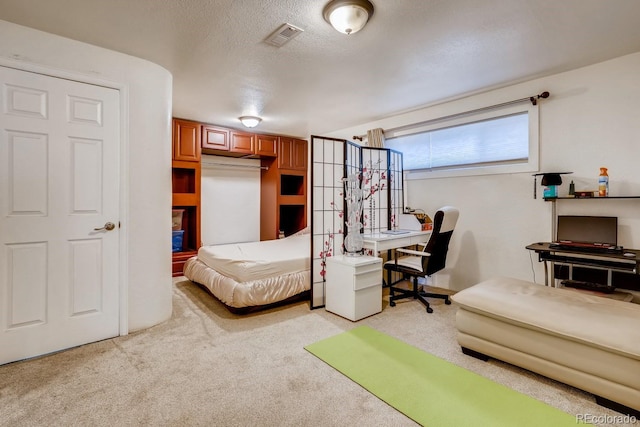 bedroom with light colored carpet, a textured ceiling, and visible vents