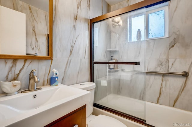bathroom with shower / bath combination with glass door, tile walls, toilet, and vanity