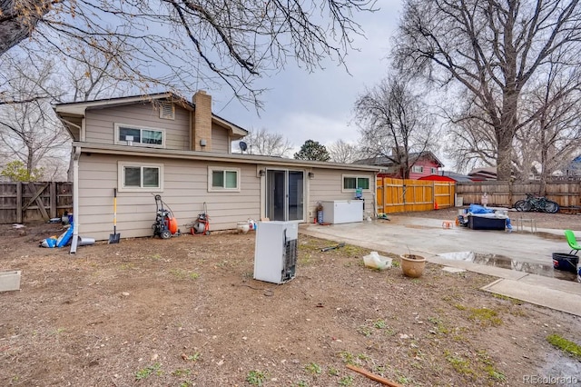 rear view of property with a fenced backyard, a chimney, and a patio