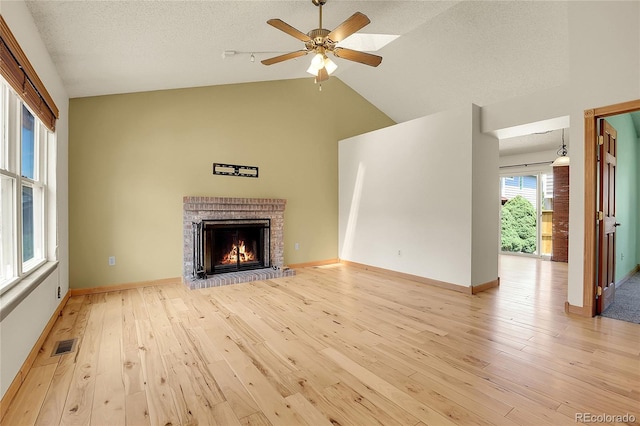 8376 Cobblestone St, Highlands Ranch, CO 80126 - unfurnished living room with light wood-type flooring, a fireplace, lofted ceiling, a ceiling fan, and a textured ceiling