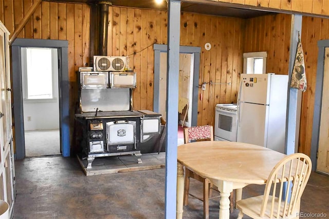 kitchen with wooden walls, a wood stove, and white appliances