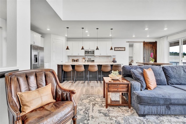 living room with a barn door and light hardwood / wood-style floors