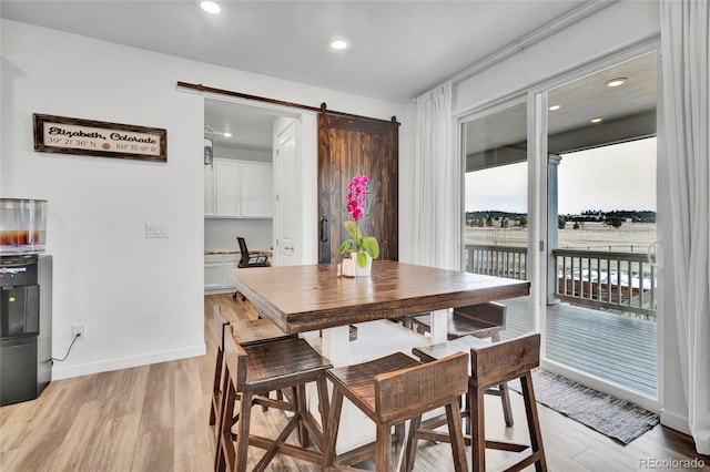 dining area featuring a barn door and light wood-type flooring