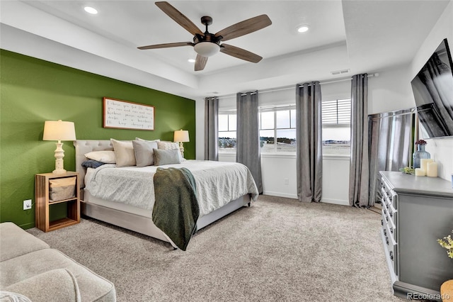 carpeted bedroom with a tray ceiling and ceiling fan