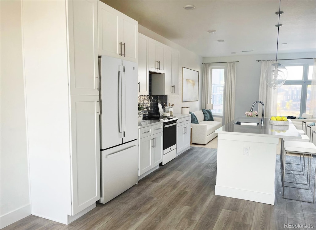 kitchen with white cabinets, decorative light fixtures, white appliances, and a center island with sink