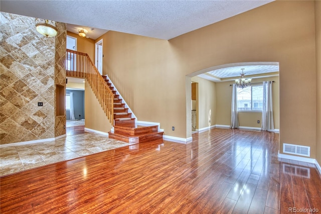 unfurnished living room with a textured ceiling, hardwood / wood-style flooring, and a notable chandelier