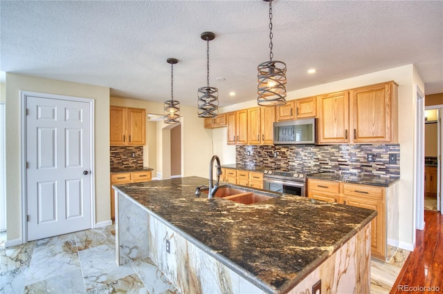 kitchen featuring decorative backsplash, appliances with stainless steel finishes, decorative light fixtures, and sink