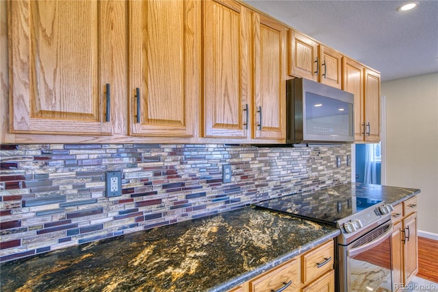 kitchen featuring backsplash, dark stone countertops, electric range, and a textured ceiling