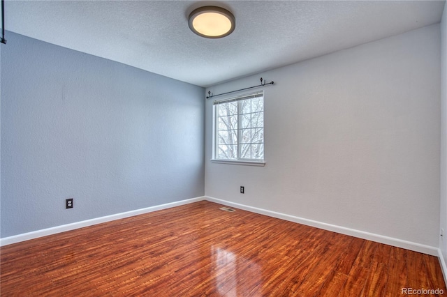 spare room with a textured ceiling and hardwood / wood-style flooring