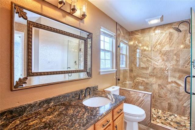 bathroom featuring a textured ceiling, vanity, toilet, and an enclosed shower