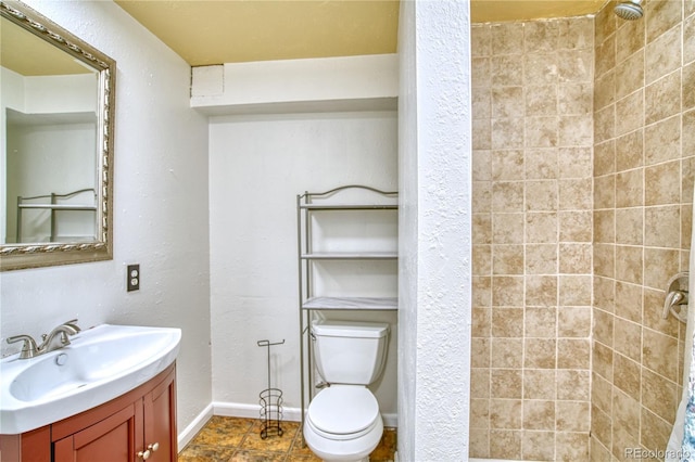 bathroom featuring tiled shower, vanity, and toilet