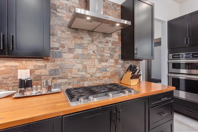 16985 County Road 306, Buena Vista, CO 81211 - kitchen with wall chimney range hood, appliances with stainless steel finishes, decorative backsplash, butcher block countertops, and dark cabinetry