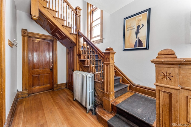 staircase with baseboards, hardwood / wood-style floors, and radiator heating unit