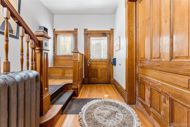 foyer featuring radiator, baseboards, light wood finished floors, and stairs