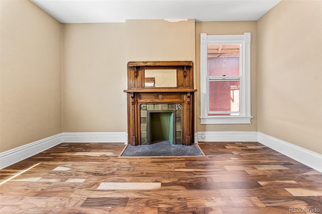 unfurnished living room featuring a fireplace, baseboards, and wood finished floors