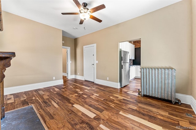 interior space with ceiling fan, dark wood-style flooring, radiator heating unit, and baseboards