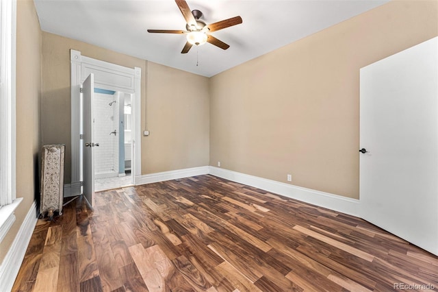 empty room featuring dark wood-type flooring, a ceiling fan, and baseboards