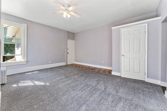 carpeted empty room with ceiling fan and baseboards