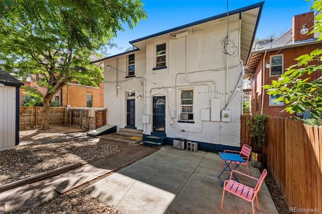 back of house with entry steps, brick siding, a patio, and a fenced backyard