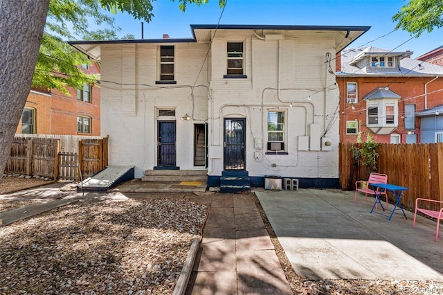 back of property featuring entry steps, a patio area, fence, and brick siding