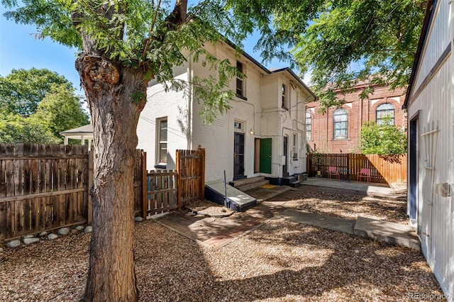 back of property featuring entry steps, a patio area, brick siding, and fence