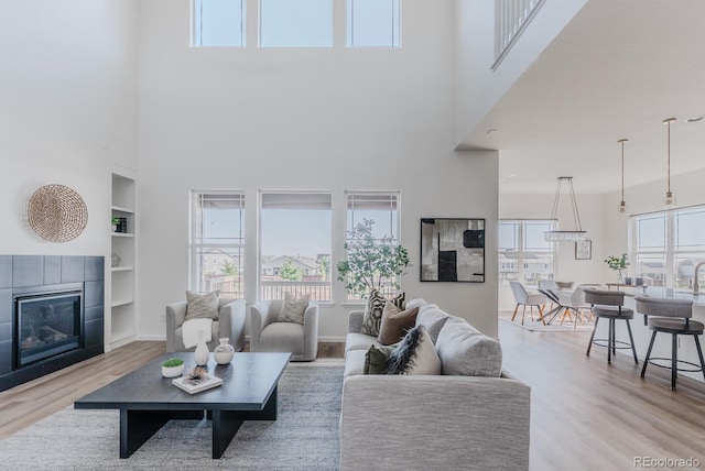 14345 Dahlia St, Thornton, CO 80602 - living room featuring a towering ceiling, built in shelves, a fireplace, plenty of natural light, and wood finished floors