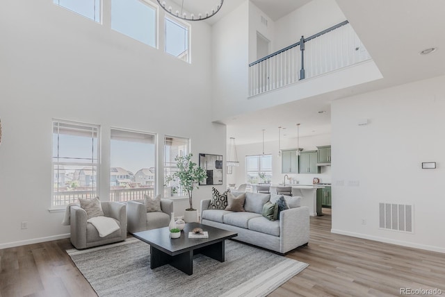 14345 Dahlia St, Thornton, CO 80602 - living area featuring a towering ceiling, plenty of natural light, light wood-type flooring, and a chandelier
