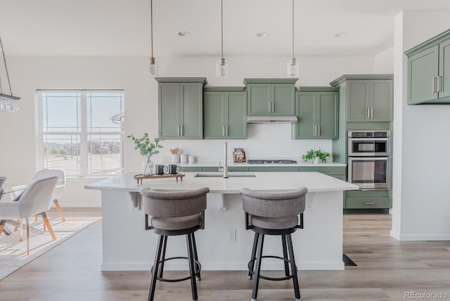 14345 Dahlia St, Thornton, CO 80602 - kitchen featuring green cabinetry, light countertops, a breakfast bar area, hanging light fixtures, and recessed lighting