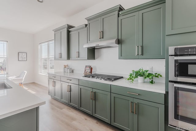 14345 Dahlia St, Thornton, CO 80602 - kitchen with appliances with stainless steel finishes, green cabinetry, under cabinet range hood, and light countertops