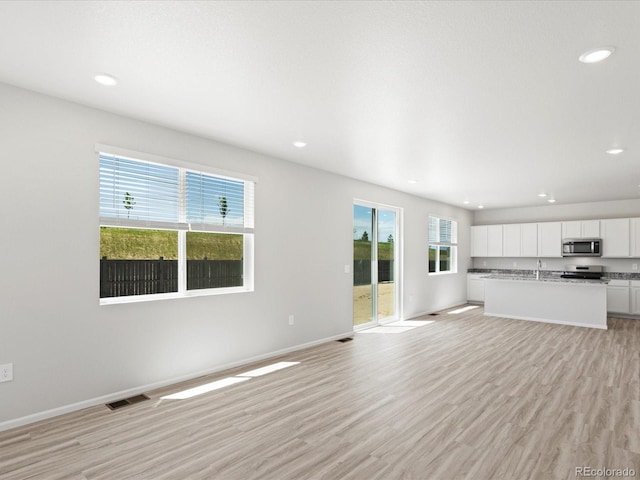7324 27th Street Ln, Greeley, CO 80634 - unfurnished living room with recessed lighting, light wood finished floors, and baseboards