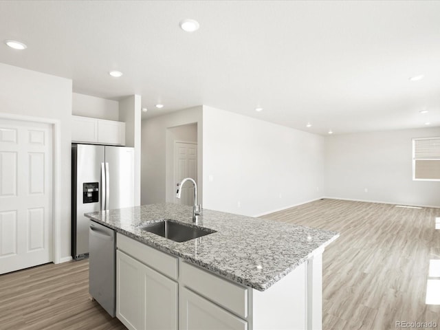 7324 27th Street Ln, Greeley, CO 80634 - kitchen with a sink, appliances with stainless steel finishes, light wood finished floors, a center island with sink, and light stone countertops