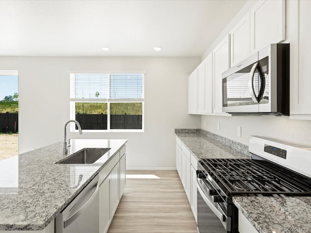 7324 27th Street Ln, Greeley, CO 80634 - kitchen with appliances with stainless steel finishes, a sink, light wood finished floors, an island with sink, and baseboards