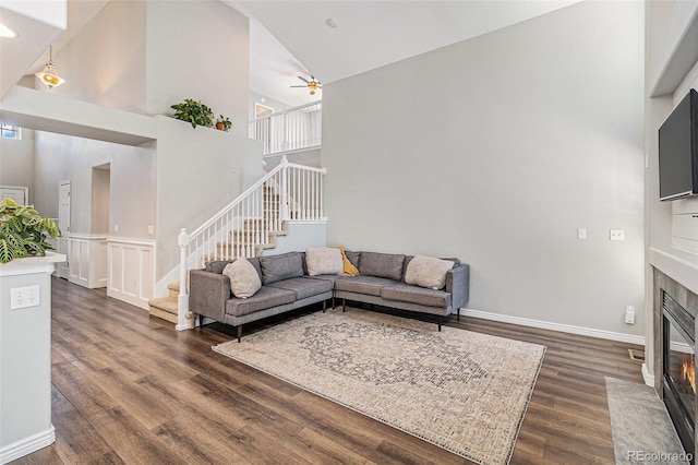 6230 Snowberry Ave, Firestone, CO 80504 - living area featuring stairway, a high ceiling, dark wood-style floors, a fireplace with flush hearth, and ceiling fan