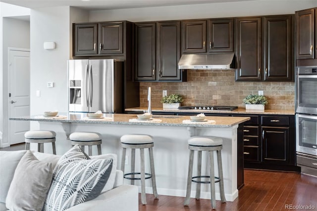 18180 W 84th Pl, Arvada, CO 80007 - kitchen with stainless steel appliances, exhaust hood, a breakfast bar, dark wood finished floors, and tasteful backsplash