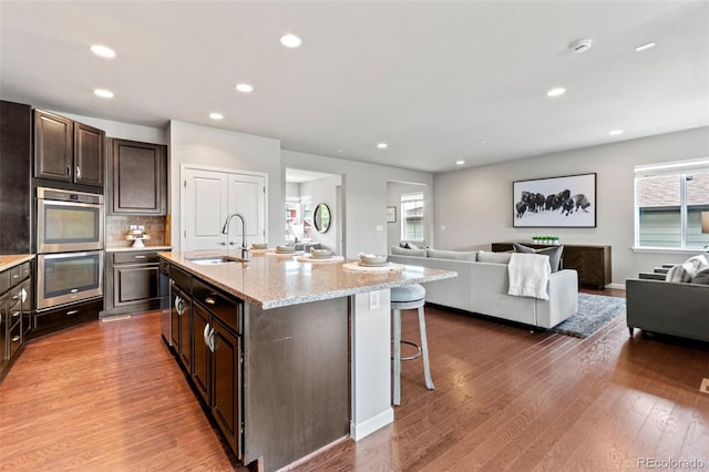 18180 W 84th Pl, Arvada, CO 80007 - kitchen featuring double oven, open floor plan, healthy amount of natural light, a breakfast bar, and recessed lighting