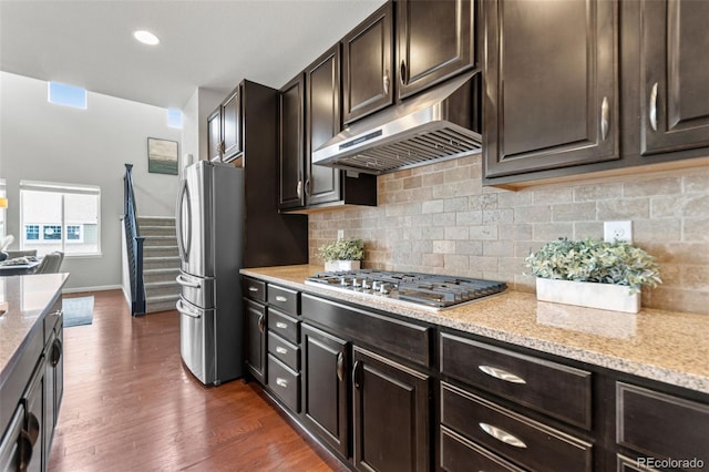 18180 W 84th Pl, Arvada, CO 80007 - kitchen with appliances with stainless steel finishes, under cabinet range hood, backsplash, and dark wood-style flooring