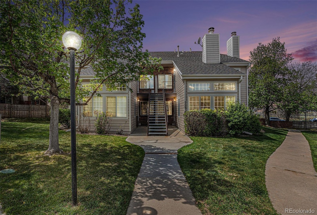 13762 E Lehigh Ave Unit G, Aurora, CO 80014 - view of front facade featuring a chimney, fence, a balcony, a yard, and stairs