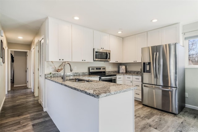 2240 Flintwood Dr, Colorado Springs, CO 80910 - kitchen featuring stainless steel appliances, light stone counters, white cabinetry, recessed lighting, and a peninsula