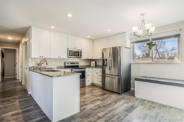 2240 Flintwood Dr, Colorado Springs, CO 80910 - kitchen featuring appliances with stainless steel finishes, dark stone counters, white cabinets, a peninsula, and recessed lighting