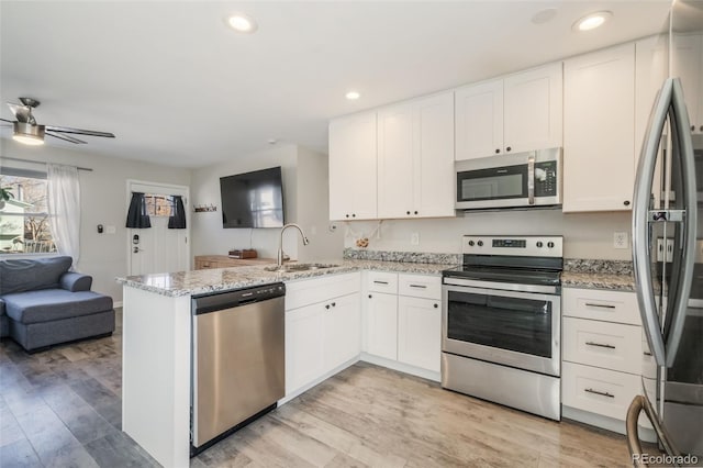 2240 Flintwood Dr, Colorado Springs, CO 80910 - kitchen featuring appliances with stainless steel finishes, open floor plan, a peninsula, white cabinetry, and recessed lighting