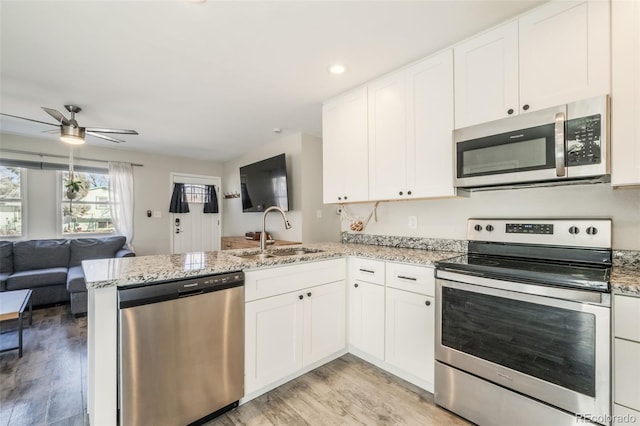 2240 Flintwood Dr, Colorado Springs, CO 80910 - kitchen featuring stainless steel appliances, a peninsula, open floor plan, ceiling fan, and light wood-type flooring