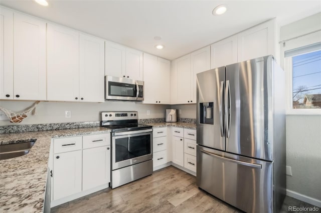 2240 Flintwood Dr, Colorado Springs, CO 80910 - kitchen with stainless steel appliances, white cabinetry, light wood finished floors, light stone countertops, and recessed lighting