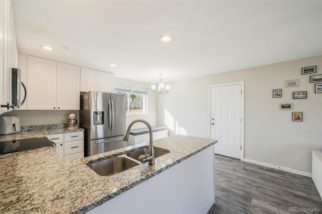 2240 Flintwood Dr, Colorado Springs, CO 80910 - kitchen with stainless steel appliances, white cabinetry, light stone countertops, a chandelier, and dark wood-style floors