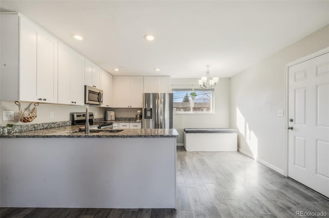 2240 Flintwood Dr, Colorado Springs, CO 80910 - kitchen featuring stainless steel appliances, dark stone countertops, a chandelier, a peninsula, and white cabinetry
